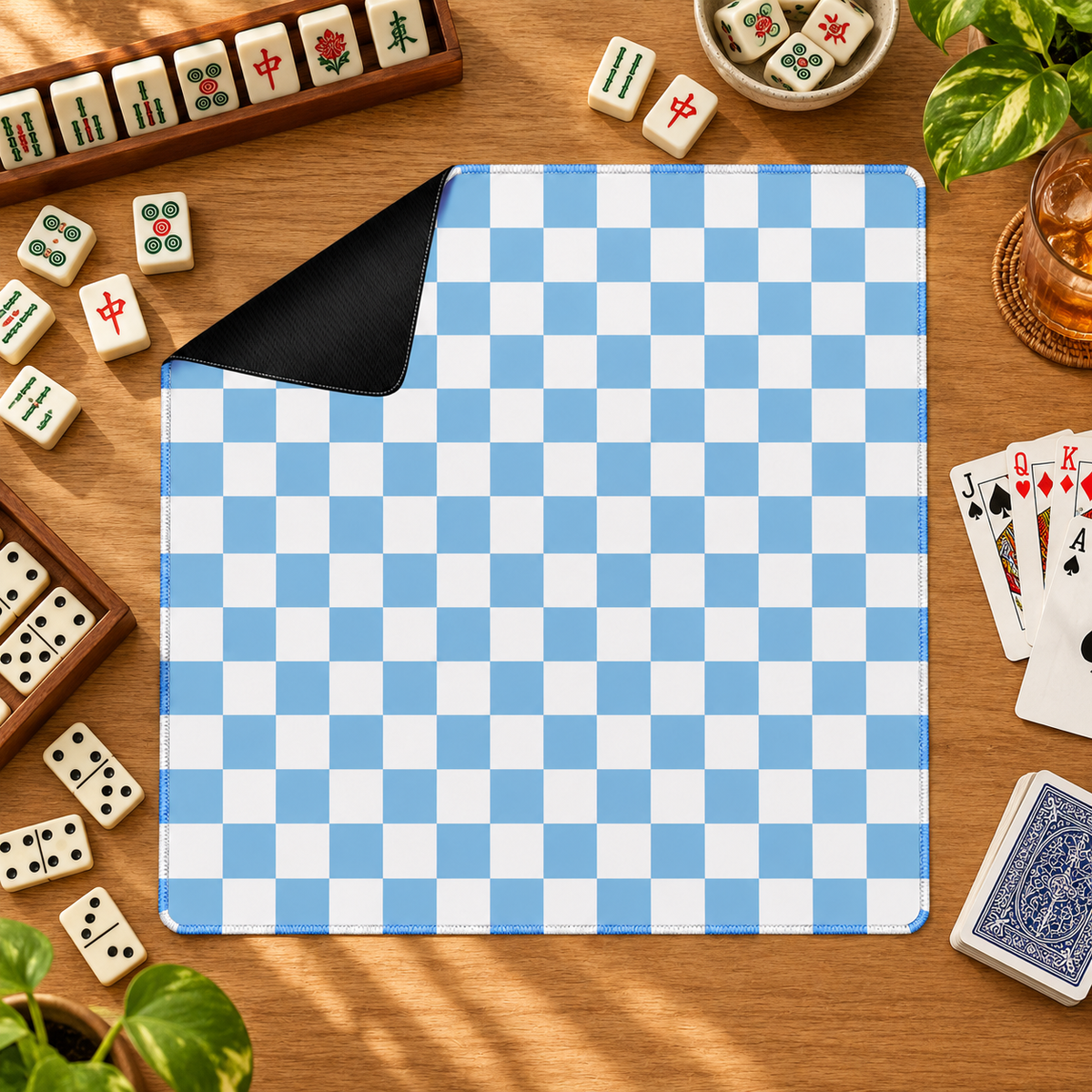 Checker blue mahjong mat with mahjong tiles, playing cards and dominoes as props outside the mat