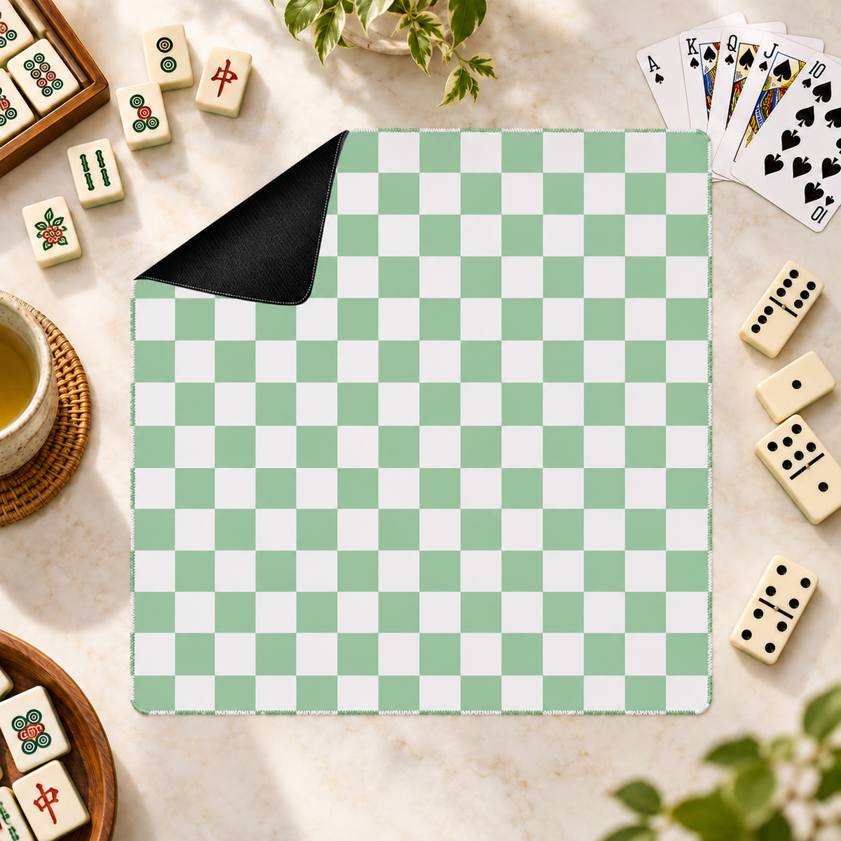 Checker green mahjong mat with mahjong tiles, playing cards and dominoes as props outside the mat